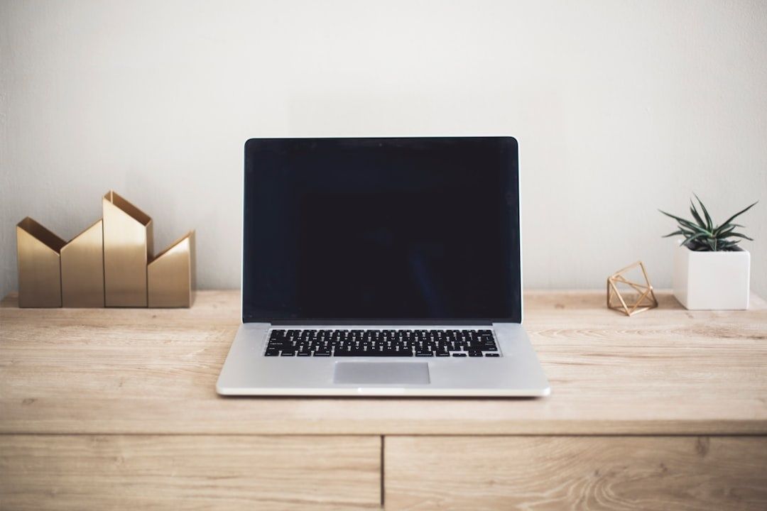 Öppen bärbar dator på ett minimalistiskt skrivbord med en växt